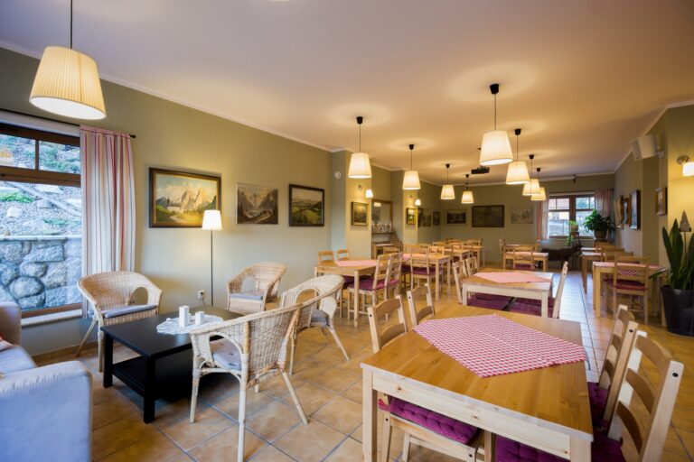 Sala restauracyjna z rzędami stołów, projektorem i przeszklonym wyjściem do ogrodu