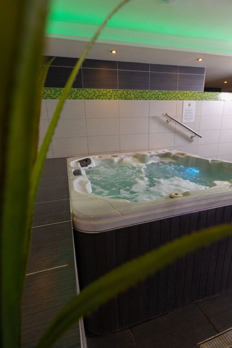 Wanna z hydromasażem z bulgoczącą wodą w strefie SPA wykończonej grafitowymi płytkami i zieloną mozaiką