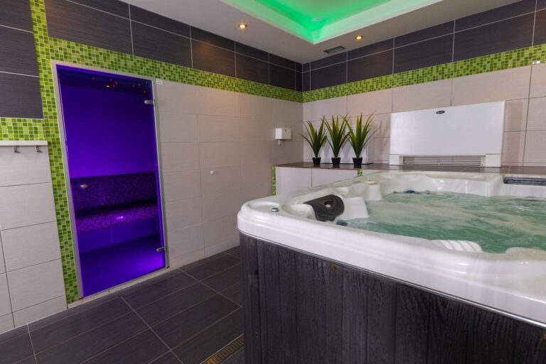 Strefa SPA z wanną z hydromasażem, przeszkloną kabiną łaźni parowej i zielono-grafitową aranżacją wykończenia